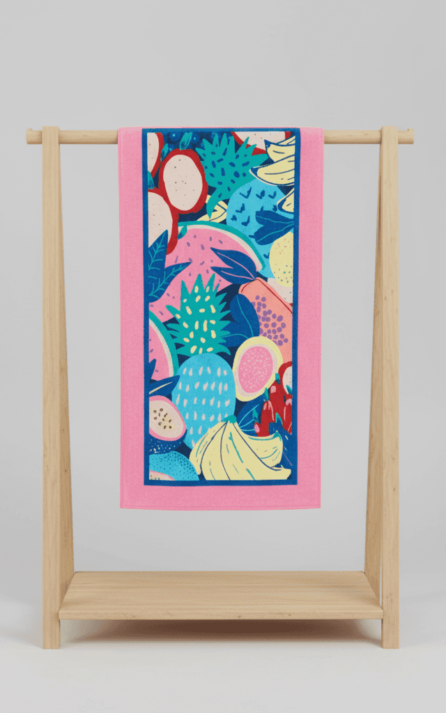 Pink towel with vibrant graphic tropical fruit pattern featuring exotic fruits and blue border